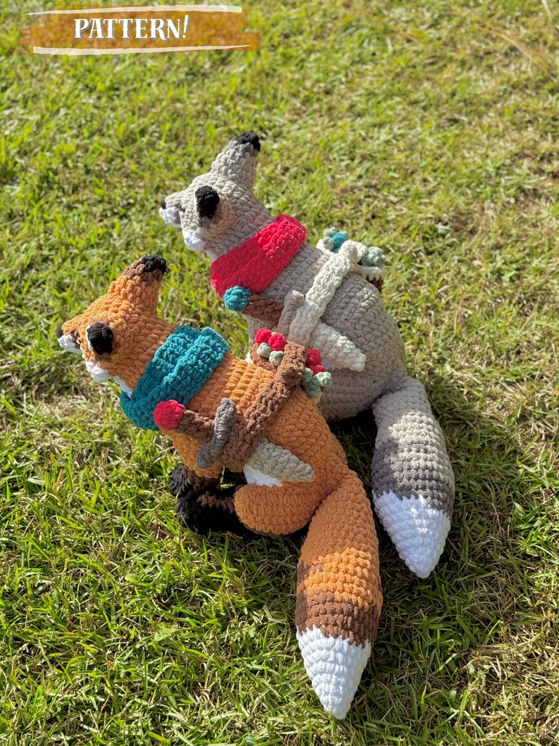 K&ouml;nnte beinhalten: Zwei geh&auml;kelte Fuchs- und Eichh&ouml;rnchen-Pl&uuml;schtiere auf gr&uuml;nem Gras. Der Fuchs ist orange und braun mit einem t&uuml;rkisfarbenen Schal, und das Eichh&ouml;rnchen ist grau mit einem roten Schal. Der Text "PATTERN!" steht oben.