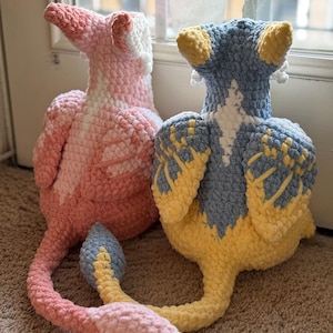 May include: Two handmade crochet plush toys. One is pink and white, the other is blue and yellow. Both have long tails and are sitting on a brown carpet. The text "PATTERN!" is visible at the bottom.