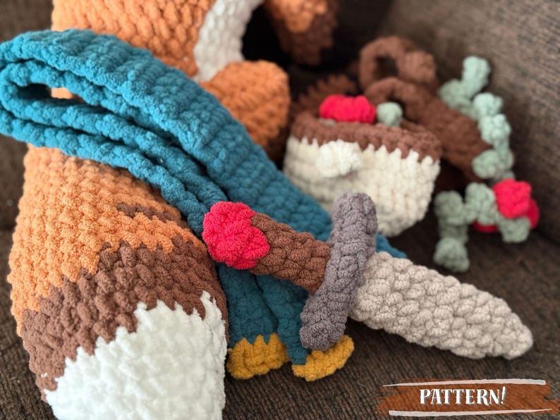 K&ouml;nnte beinhalten: Geh&auml;keltes Fuchspielzeug mit blauem Schal, Schwert und Kuchen. Der Fuchs ist orange, braun und wei&szlig;. Das Schwert ist grau, braun und rot. Der Kuchen ist wei&szlig; und braun. Das Wort "PATTERN!" ist im Bild.