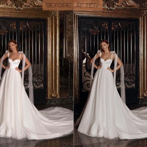 May include: A white wedding dress with a sweetheart neckline and a long train. The dress has tulle straps with bows on the shoulders. The model is standing in front of a gold-coloured door.