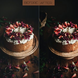 May include: A white cake with whipped cream frosting decorated with fresh strawberries and purple flowers. The cake is on a wooden cake stand and there are flower petals scattered on the wooden table.