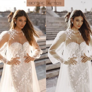 May include: A bride wearing a white lace wedding dress with a sheer overlay and puff sleeves. The dress has a sweetheart neckline and a fitted bodice. The bride is standing on a set of stairs with a stone background.