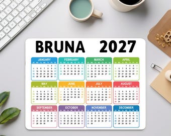 May include: A rectangular 2027 calendar mouse pad featuring the name BRUNA in bold black text at the top. The calendar displays all twelve months in a grid, each color-coded with distinct borders for January through December, organized in rows.
