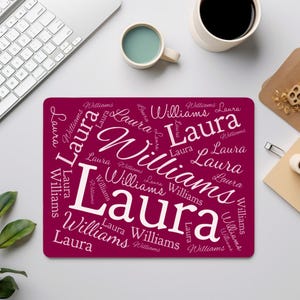 May include: A rectangular, burgundy mousepad with the name "Laura Williams" in a white, stylized font. The name is repeated in various sizes and orientations across the surface, creating a personalized design.