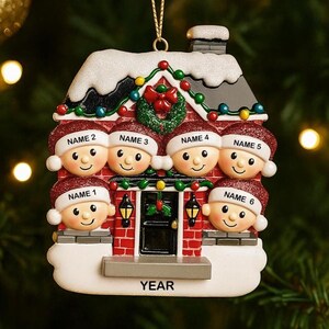 May include: A personalized Christmas ornament shaped like a house, featuring six smiling faces wearing Santa hats. The house is red brick with a snowy roof, a wreath, and string lights. The word "YEAR" is at the bottom.