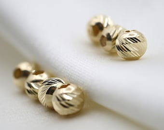 May include: Three gold-colored round beads with a textured surface.