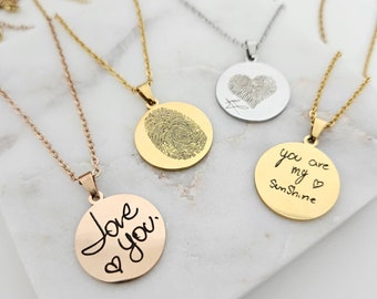 Puede incluir: Tres collares de oro con diferentes colgantes. Un colgante tiene un diseño de huella digital, otro tiene las palabras "you are my sunshine" y el último tiene las palabras "love you" con un corazón.