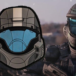 Könnte beinhalten: Ein grauer und blauer Militärhelm mit einem weißen Streifen oben. Der Helm ist ein Patch mit einem weißen Umriss. Der Helm ist ein beliebtes Design für Militär- und Science-Fiction-Fans.