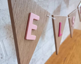 May include: Wooden triangle banner with the letters "ELS" in pink painted on each triangle.