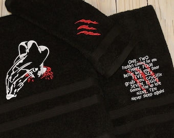 May include: Black bath towel with a white embroidered image of Freddy Krueger's glove and hat. The towel has red embroidered claw marks and the text "ONE, TWO Freddy's coming for you THREE, FOUR lock you Door FIVE SIX grab you crucifix SEVEN, EIGHT Genna thay to late NINE, TEN Never sleep again".