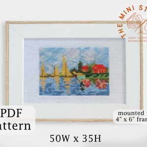 May include: A cross stitch pattern of a colorful landscape with sailboats, houses, and trees. The pattern is framed in a white frame with a wooden border. The pattern is 50 stitches wide and 35 stitches high. The pattern is mounted in a 4 inch by 6 inch frame.