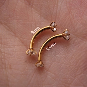 Puede incluir: Dos piezas de joyer&iacute;a corporal de barra curva dorada con gemas de cristal transparente. La pieza superior est&aacute; etiquetada como "8 mm" y la pieza inferior est&aacute; etiquetada como "10 mm".