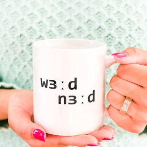 Peut inclure: Une tasse en céramique blanche avec du texte noir qui dit "w3:d n3:d".