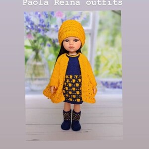 May include: A doll dressed in a yellow knitted hat, cardigan, and dress, with a navy blue top and boots. The dress features a checkered pattern. The image includes the text "Paola Reina outfits".