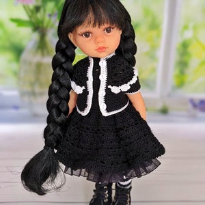 May include: A black and white crocheted dress with a white crocheted collar and sleeves. The doll has long black hair in braids and is wearing black boots.