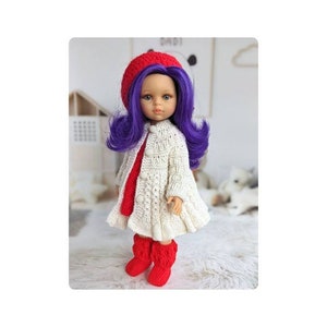 May include: A doll with purple hair, wearing a red beret, a white knitted coat, a red dress, and red boots. The doll is standing on a white, fluffy surface.