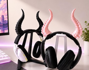 Può includere: Due supporti per cuffie con accenti a forma di corno. Un supporto è nero con corna nere, l'altro è bianco con corna rosa. Ogni supporto contiene un paio di cuffie. Le cuffie sono nere e bianche.