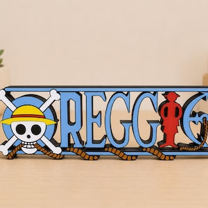 Puede incluir: Un letrero personalizado con el nombre REGGIE en letras azules con bordes negros. El diseño incluye una calavera blanca con huesos cruzados y un sombrero de paja amarillo a la izquierda, y una silueta roja a la derecha, con una cuerda marrón.