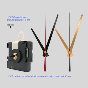 Könnte beinhalten: Ein schwarzes funkgesteuertes Uhrwerk mit einem Zeigersatz von 12 cm. Das Bild zeigt den Uhrwerkmechanismus zusammen mit schwarzen und goldenen Zeigern. Der Text auf dem Bild lautet "DCF radio-controlled clock movement with hand set 12 cm."