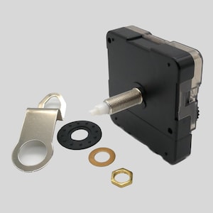 Könnte beinhalten: Ein schwarzes Uhrwerk mit einer silbernen Gewindewelle, einem silbernen Metallbügel und verschiedenen kleinen Hardware-Teilen. Die Hardware umfasst eine schwarze Gummiunterlegscheibe, eine goldfarbene Unterlegscheibe und eine sechseckige Mutter.