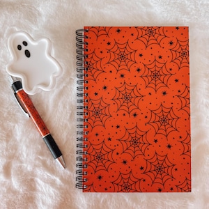 Cuaderno espiral naranja con telarañas espeluznantes / Tapa suave al tacto / 80 páginas con renglones universitarios