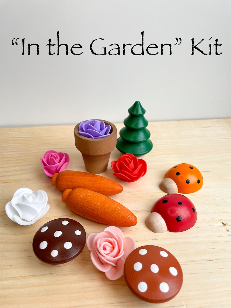 Puede incluir: Un juego de madera con el t&iacute;tulo "In the Garden" Kit. El juego incluye un peque&ntilde;o &aacute;rbol de madera, dos setas con lunares blancos, dos mariquitas, una zanahoria, una maceta con una flor morada y tres flores rosas.