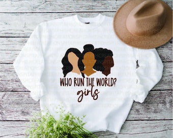 Może przedstawiać: Biała bluza z brązową grafiką przedstawiającą trzy kobiece twarze i tekst "Who run the world? girls".
