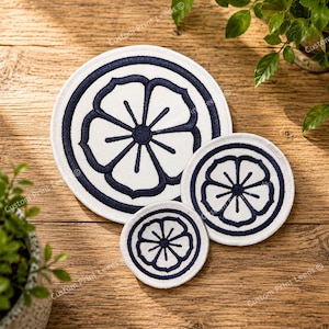 May include: Three circular embroidered patches in varying sizes, each featuring a white background with a dark navy blue stitched floral motif. The design consists of a central circle surrounded by six symmetrical petals enclosed within a thick navy border.
