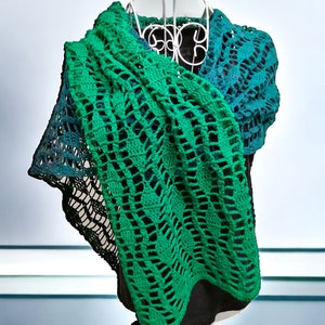 May include: A green and teal crochet shawl with a lacy pattern. The shawl is draped over a white mannequin.