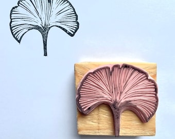 May include: A wooden stamp with a pink ginkgo leaf design. The stamp is on a white background.