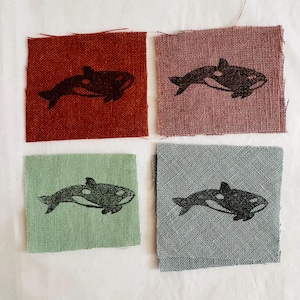 Peut inclure: Quatre carrés de tissu avec une silhouette noire et blanche d'une orque imprimée sur chacun. Les carrés sont en rouge, rose, vert et bleu.