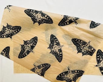 May include: Brown paper gift wrap with a black butterfly pattern. The butterflies are printed in a repeating pattern across the paper.