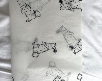 Könnte beinhalten: Weißes Geschenkpapier mit einem sich wiederholenden Muster aus schwarzen Kaninchen. Die Kaninchen sind in einer einfachen, stilisierten Art und Weise gezeichnet und schauen in verschiedene Richtungen.