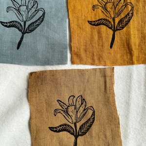 May include: Three fabric squares featuring a black floral print. The squares are in shades of blue and yellow.