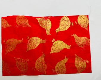 May include: Red fabric with a repeating pattern of gold birds printed on it.