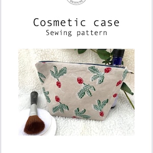 Peut inclure: Une trousse de toilette beige avec une fermeture éclair et un imprimé floral rouge et vert. La trousse est posée sur une surface blanche et moelleuse. Le texte "Poppywillmotdesigns.etsy.com" est imprimé sous la trousse.