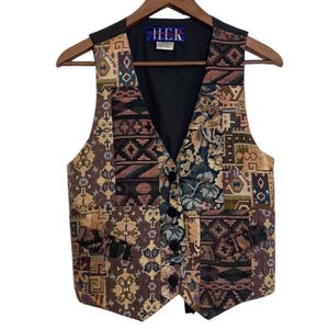 May include: A multi-coloured tapestry waistcoat with a black lining and a button fastening. The waistcoat has a patchwork design with various geometric and floral patterns. The label on the waistcoat reads "HEK".