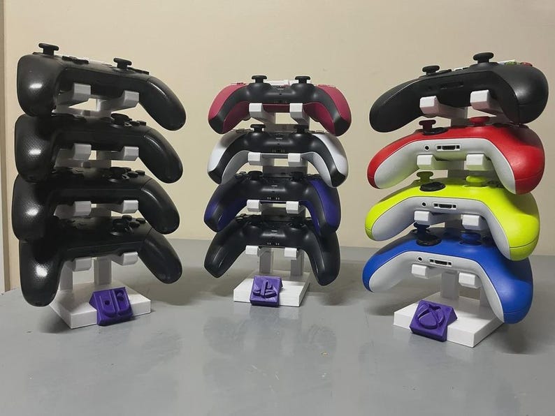 Pu&ograve; includere: Tre supporti bianchi che espongono pi&ugrave; controller di gioco. I controller sono neri, rossi, rosa, blu, gialli e bianchi. Ogni supporto ha un logo colorato alla base.
