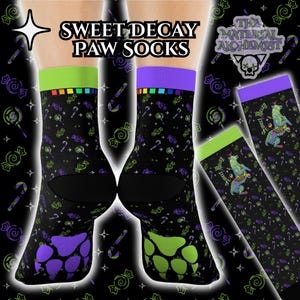 May include: Black socks featuring a candy and paw print pattern. The socks have green and purple details, with the text "Sweet Decay Paw Socks" at the top. The Material Alchemist logo is also visible.