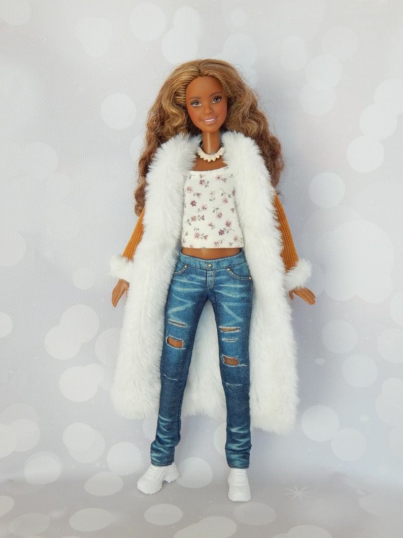 May include: A brown-haired doll wearing a white faux fur coat, a white and floral print top, blue jeans with distressed details, and white sneakers.