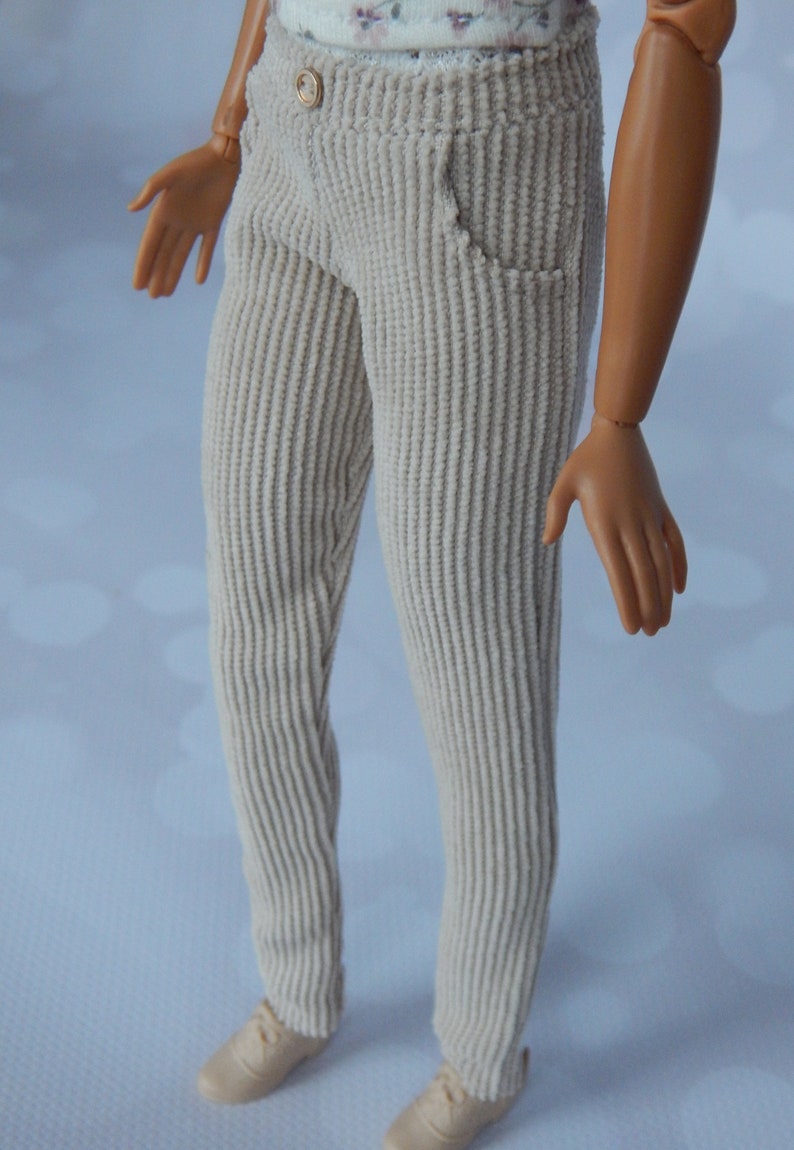May include: A pair of light beige corduroy pants. The pants have a straight leg and a slightly flared bottom.