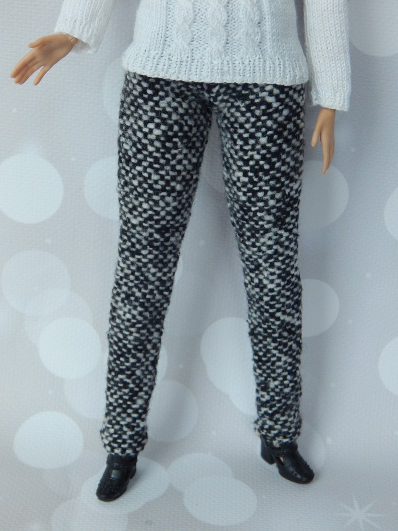 May include: Black and white patterned pants with a white sweater.