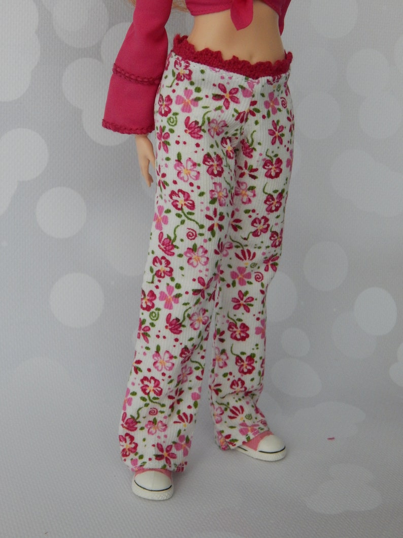 May include: White pants with a pink floral pattern and a red waistband. The pants are made of a soft, comfortable fabric and have a relaxed fit.