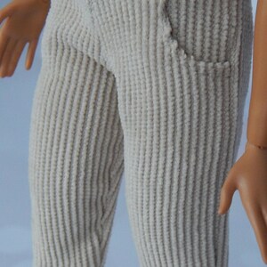 May include: Beige corduroy pants with a button closure and a pocket on the right side.