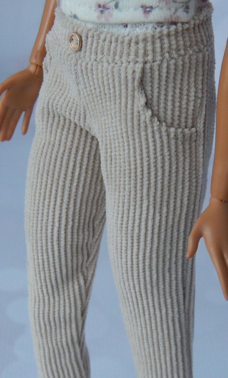 May include: Beige corduroy pants with a button closure and a pocket on the right side.