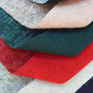 K&ouml;nnte beinhalten: Ein Stapel Stoffmuster in verschiedenen Farben, darunter Blau, Grau, Rosa, Gr&uuml;n, Rot, Wei&szlig; und Marineblau. Der Stoff ist weich und texturiert.