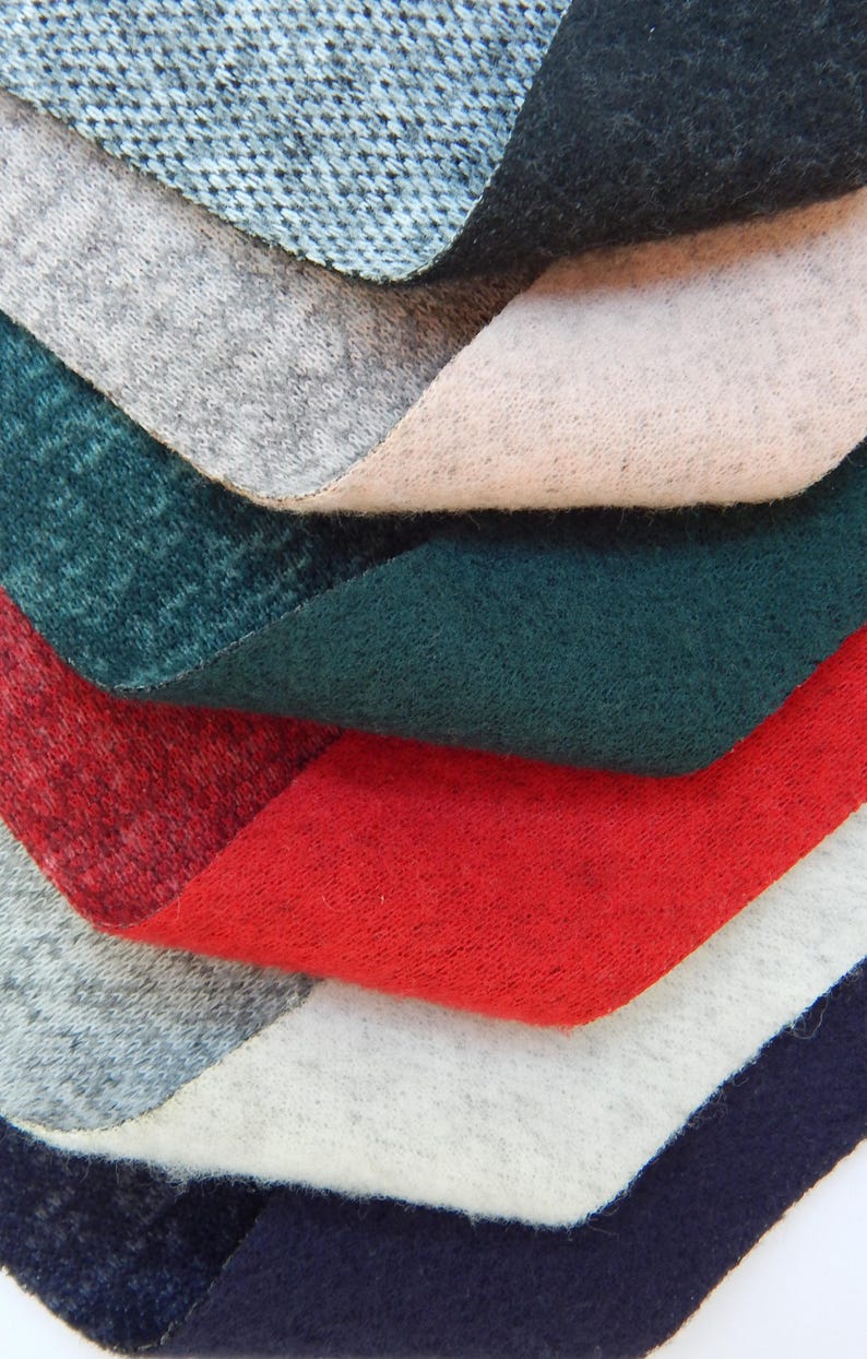 K&ouml;nnte beinhalten: Ein Stapel Stoffmuster in verschiedenen Farben, darunter Blau, Grau, Rosa, Gr&uuml;n, Rot, Wei&szlig; und Marineblau. Der Stoff ist weich und texturiert.