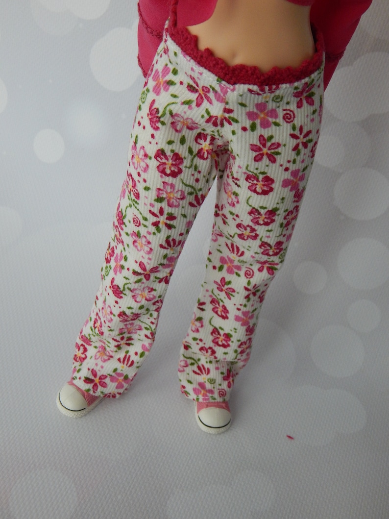May include: White pants with a pink floral pattern and a red waistband. The pants are made of a soft, comfortable fabric and have a relaxed fit.