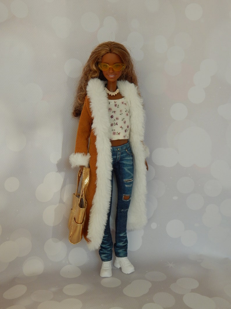 May include: A doll wearing a brown corduroy coat with a white fur trim, a white floral top, blue jeans with a distressed look, and white sneakers. The doll is holding a gold handbag and wearing yellow sunglasses.