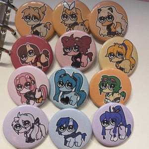 May include: A collection of twelve round pinback buttons featuring cartoon pony illustrations in various colors. Each button has a unique pony design with different hair colors and outfits, set against a solid background.